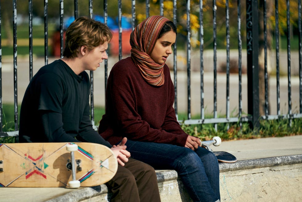 Two people sit on a concrete ledge in a park area