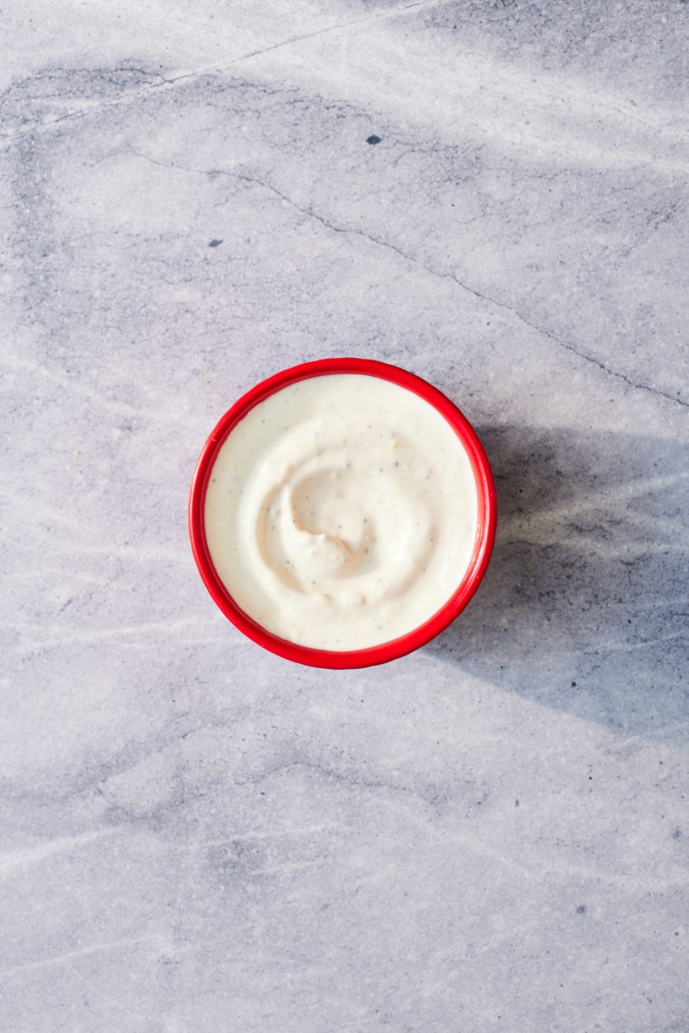 halal cart style white sauce in a red bowl on a marble background