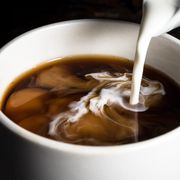 pouring creamer into a cup of coffee