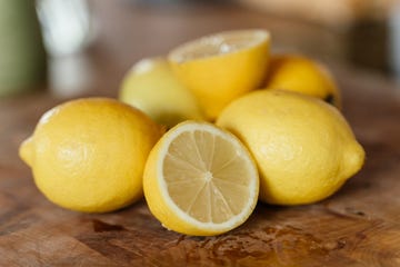 half cut lemon on a wooden cutting board with lemons
