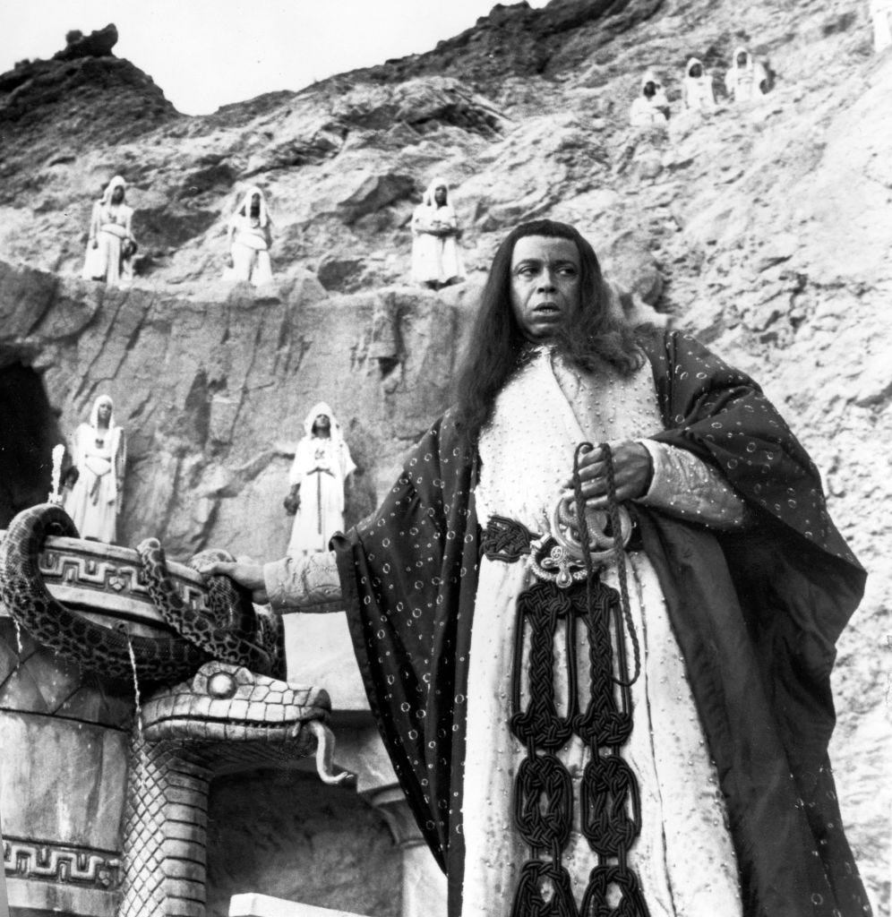 james earl jones wearing a long robe and standing next to a serpent monument on a movie set