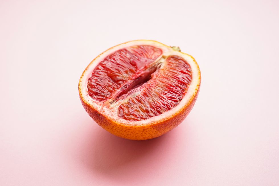 half of a blood orange on a pink background sex concept 18