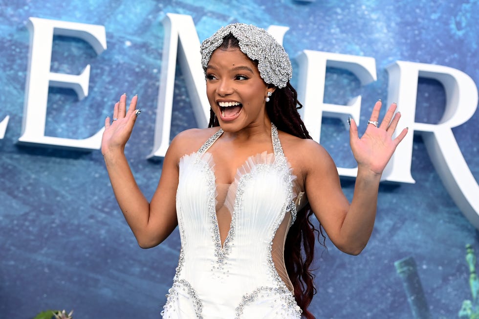 halle bailey smiling and waving with both hands at a film premiere