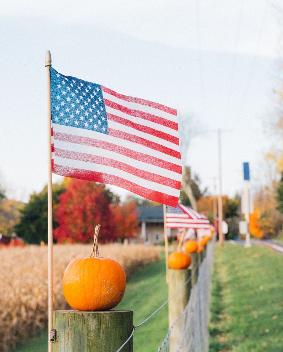 rural america patriotic pumpkins, american flag next to pumpkins as halloween decorations on farm during autumn