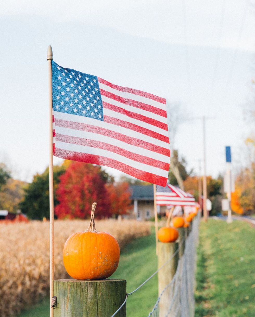 rural america patriotic pumpkins, american flag next to pumpkins as halloween decorations on farm during autumn