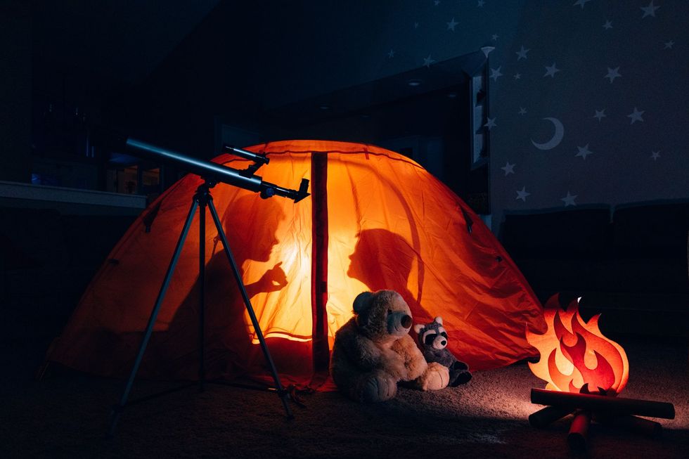 silhouette of two boys in tent camping indoors telling ghost stories for a halloween activity