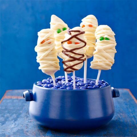 banana mummies  on sticks the sticks are set in a little blue pot filled with blue m n ms