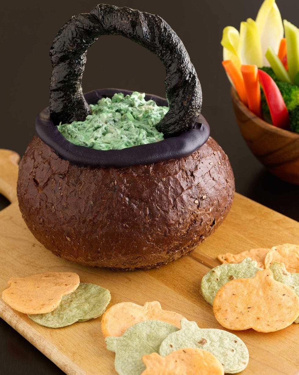 spinach dip in bread bowl with a bread handle to look like a cauldron and pumpkin shaped tortilla chips