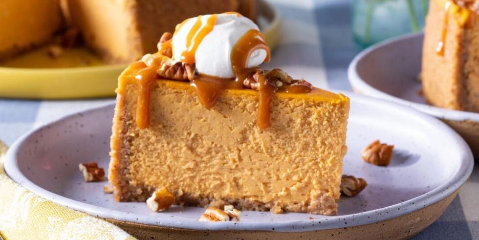 pumpkin cheesecake slice on plate with caramel and whipped cream
