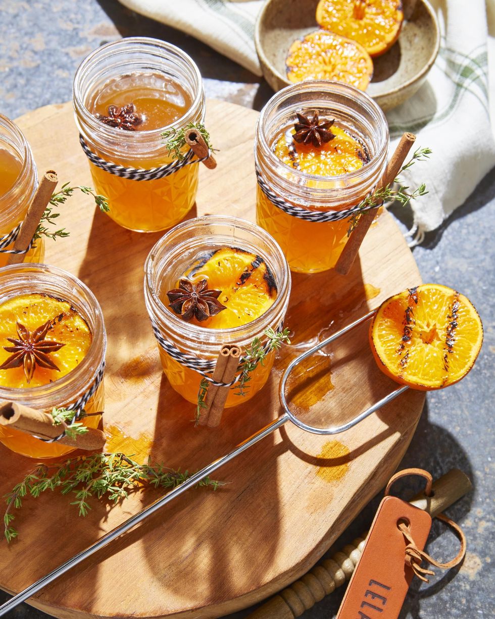 hot toddy with charred oranges in mason jars with cinnamon sticks