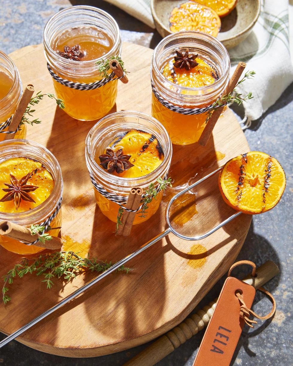 hot toddy with charred oranges in mason jars with cinnamon sticks