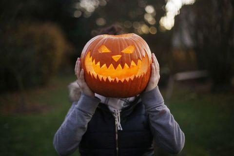 child holding jack o lantern in front of face