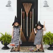 two girls wearing witch costumes with brooms