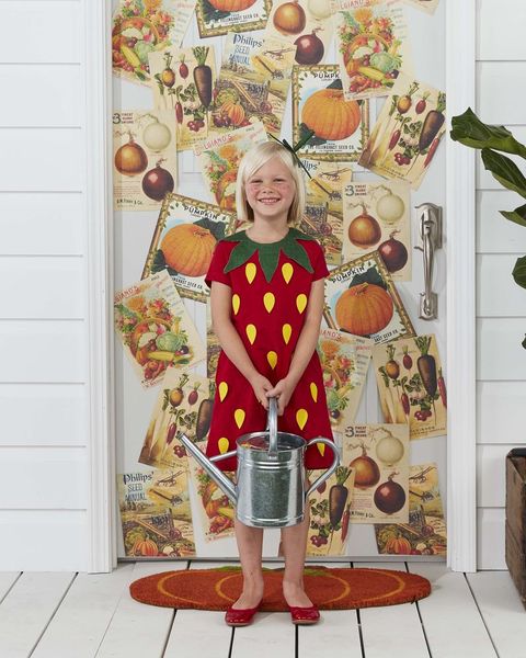 girl wearing strawberry halloween costume and holding a watering can