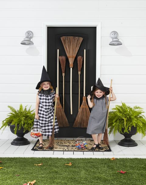 2 girls wearing halloween witch costumes with brooms, witch hats, and simple homemade black and white gingham dresses