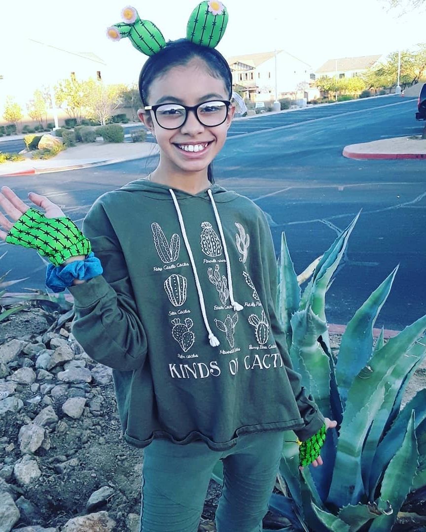 tween girl in cactus costume with cactus headband, cactus patterned fingerless gloves, green sweatshirt, green pants