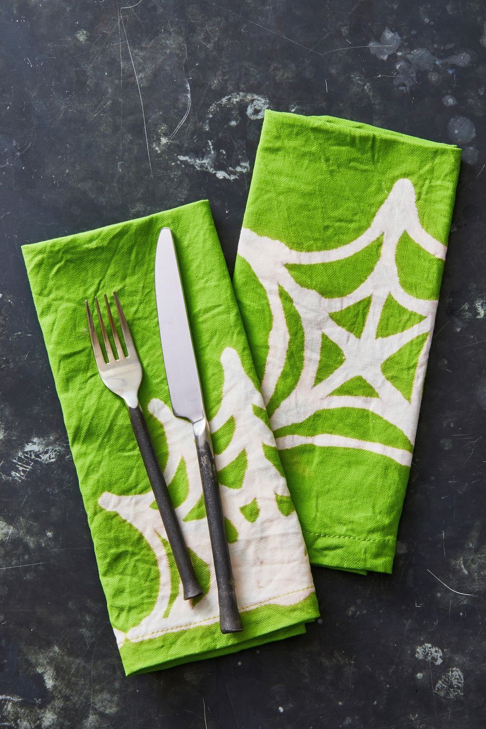 halloween crafts, two green bleach pen napkins with white spiderweb designs