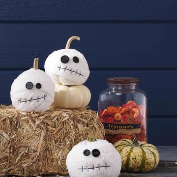 mummy pumpkins, a halloween craft for kids, displayed on haystack with plain pumpkins and jar of old orange buttons