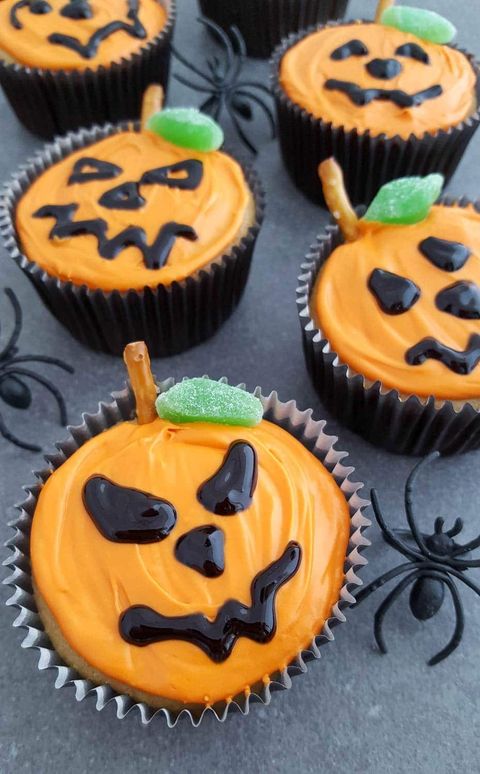 jack o lantern cupcakes with green candy and fake spiders