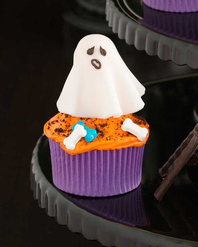cupcakes with orange frosting and a white fondant ghost on top