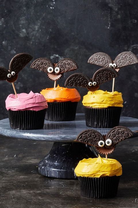 chocolate cupcakes with yellow, orange, and pink frosting with bats made of oreos on top