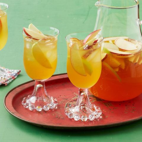 apple cider sangria in wine glasses on red tray with green background