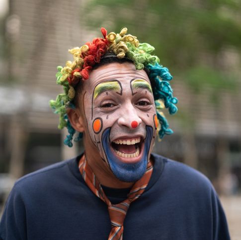 a man with colorful face paint and rainbow hair to look like a happy clown