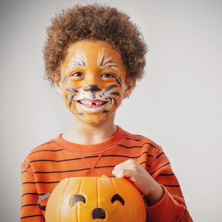 mixed race boy with tiger costume and halloween jackolantern bucket