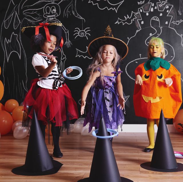 halloween games , three girls wearing costumes while throwing hoops on witch hats