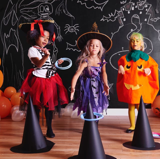 halloween games , three girls wearing costumes while throwing hoops on witch hats