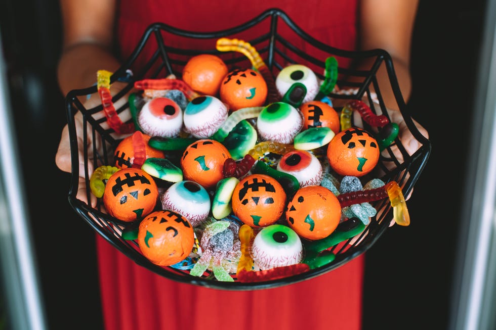 woman at the front door offering funny halloween candies in a spiderweb shaped bowl