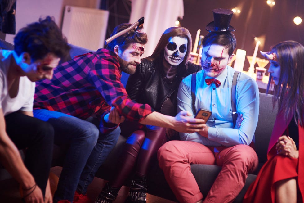 group of adults dressed in halloween makeup looking at a card