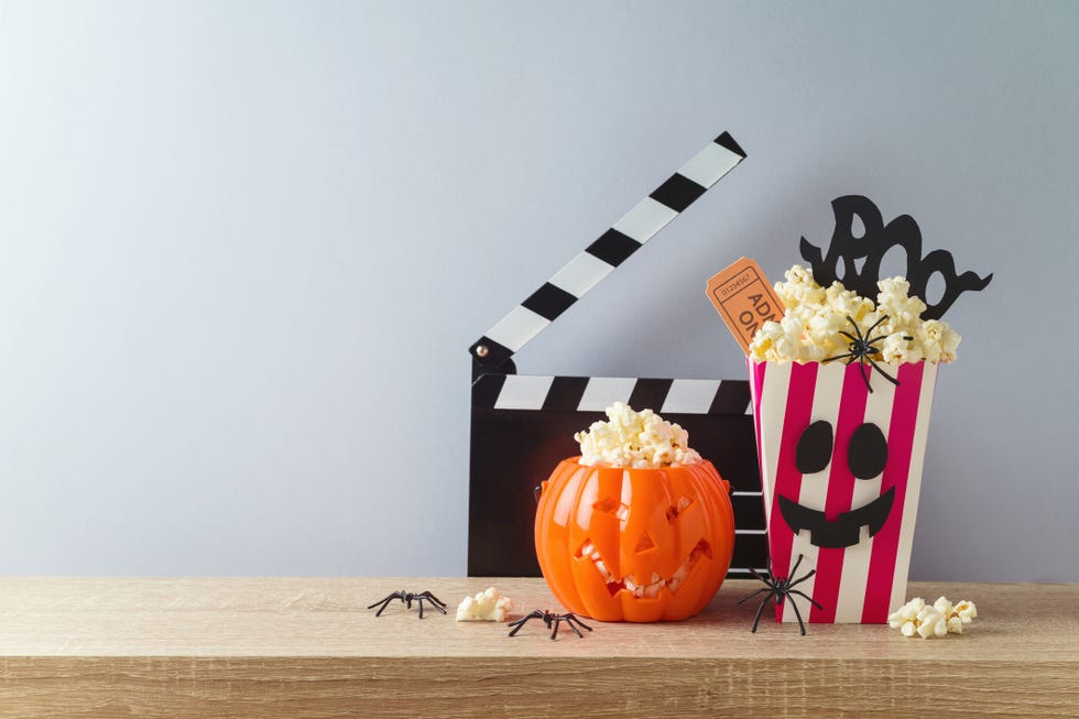 jack o lantern pumpkin, popcorn and movie clapperboard on a table
