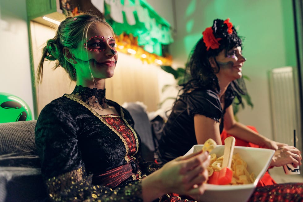 halloween games for adults, two women sitting on couch in costume
