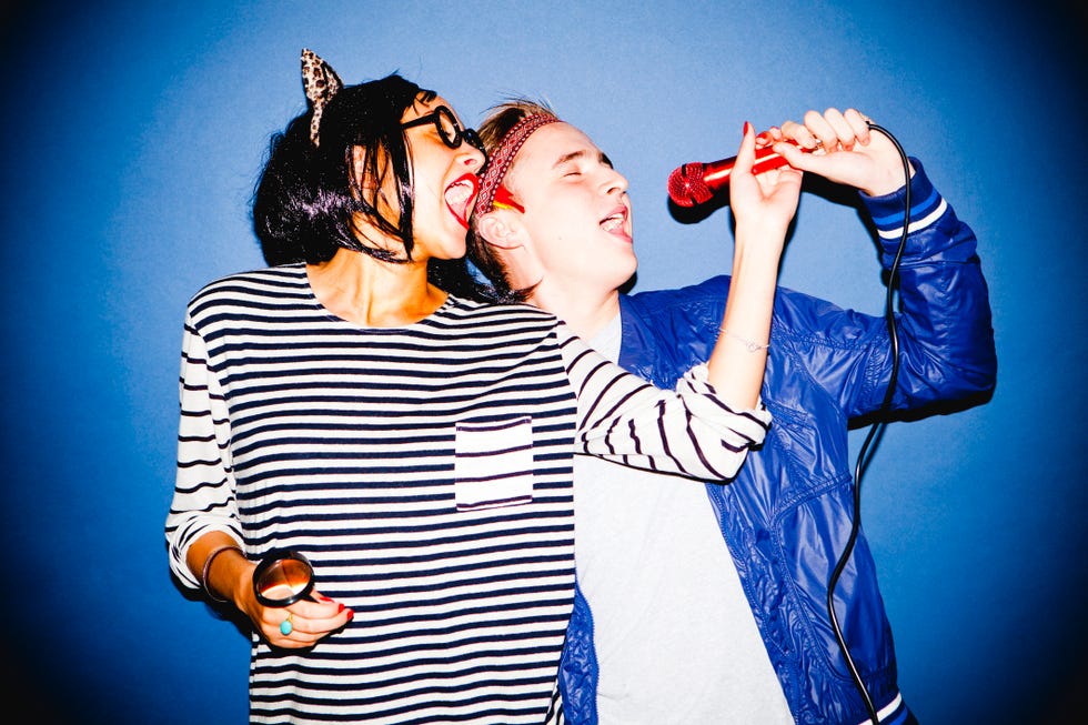 halloween games for adults portrait of a young man and woman in a fancy dress singing into a microphone standing in front of a blue backdrop