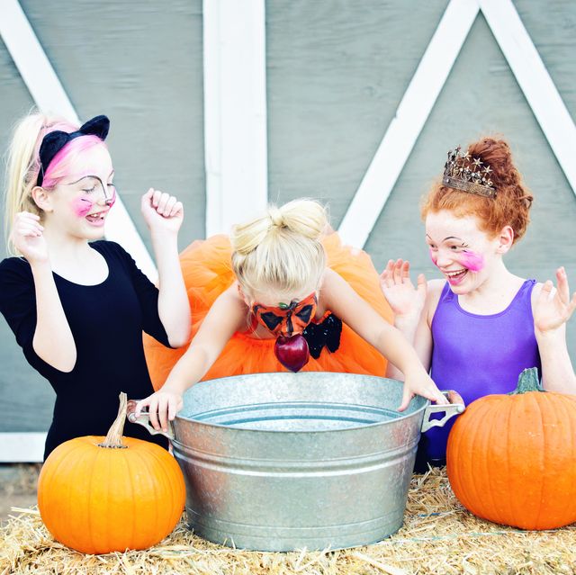 girls laughing and excited bobbing for apples at a halloween party
