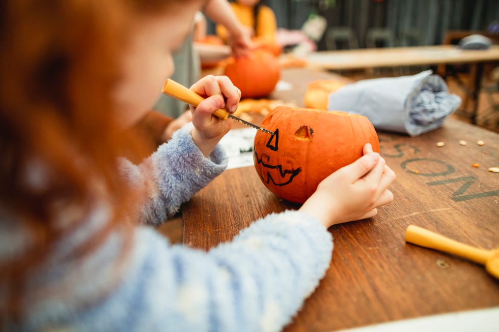 halloween games, kid carving a pumpkin and drawing faces