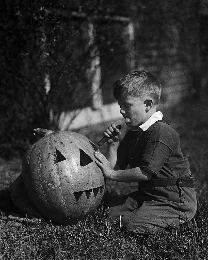vintage photograph of boy carving jack o lantern