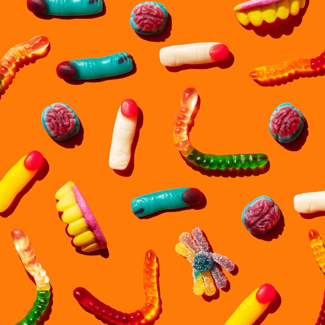Halloween jelly beans, finger-shaped, brains, worm and vampire teeth on orange background halloween candy