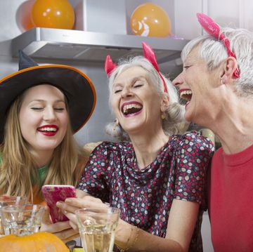 three women in halloween costumes laughing at a phone