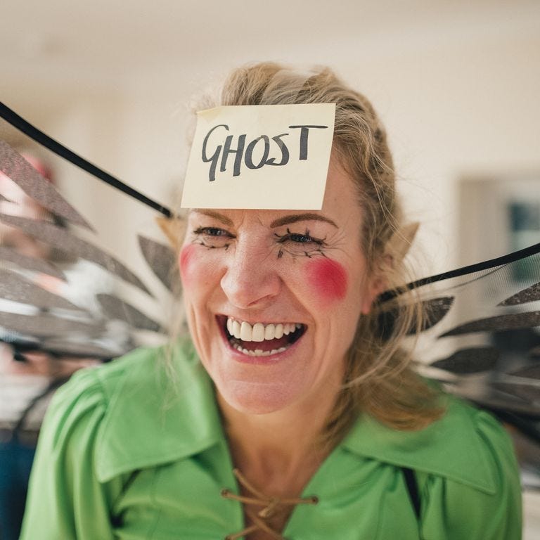 , woman smiling and wearing a label on her forehead that reads ghost