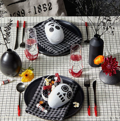 halloween party ideas, skeleton candy holder on black plates, open bottles with halloween labels