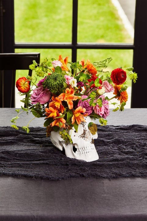 halloween party ideas, skull centerpiece on the table with flowers inside
