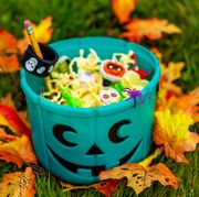 non candy halloween treats turquoise jack o lantern bin filled with non candy halloween treats on top of leaves and grass