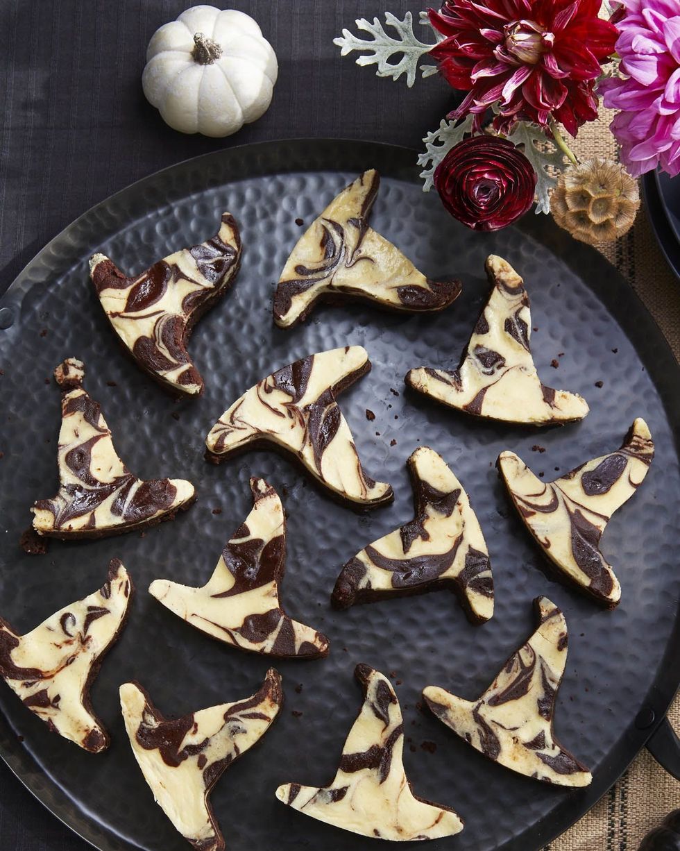 black bottom brownies cut out in the shape of witch hats arranged on a black serving plate