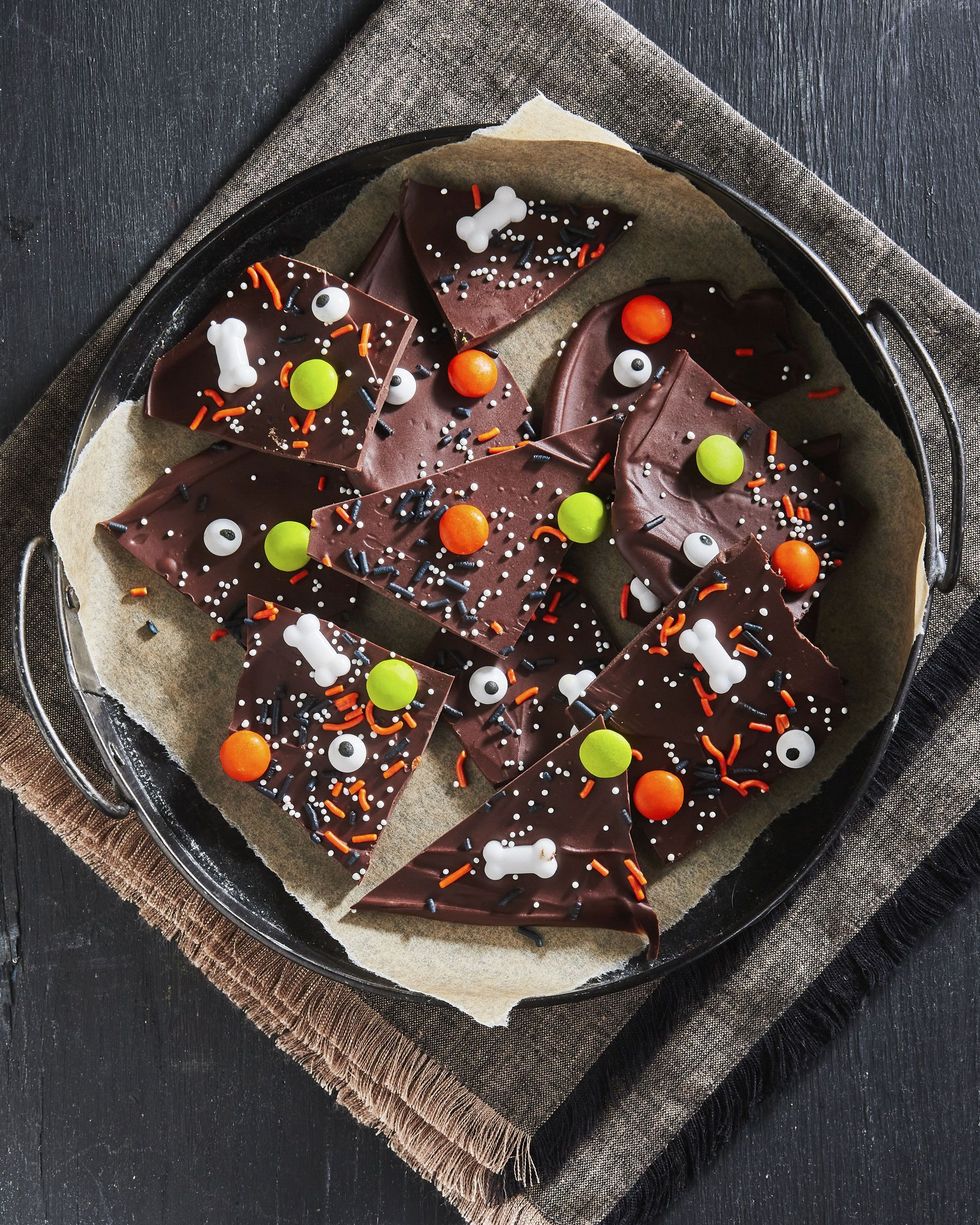 halloween candy bark broken into pieces and arranged on a parchment lined tray