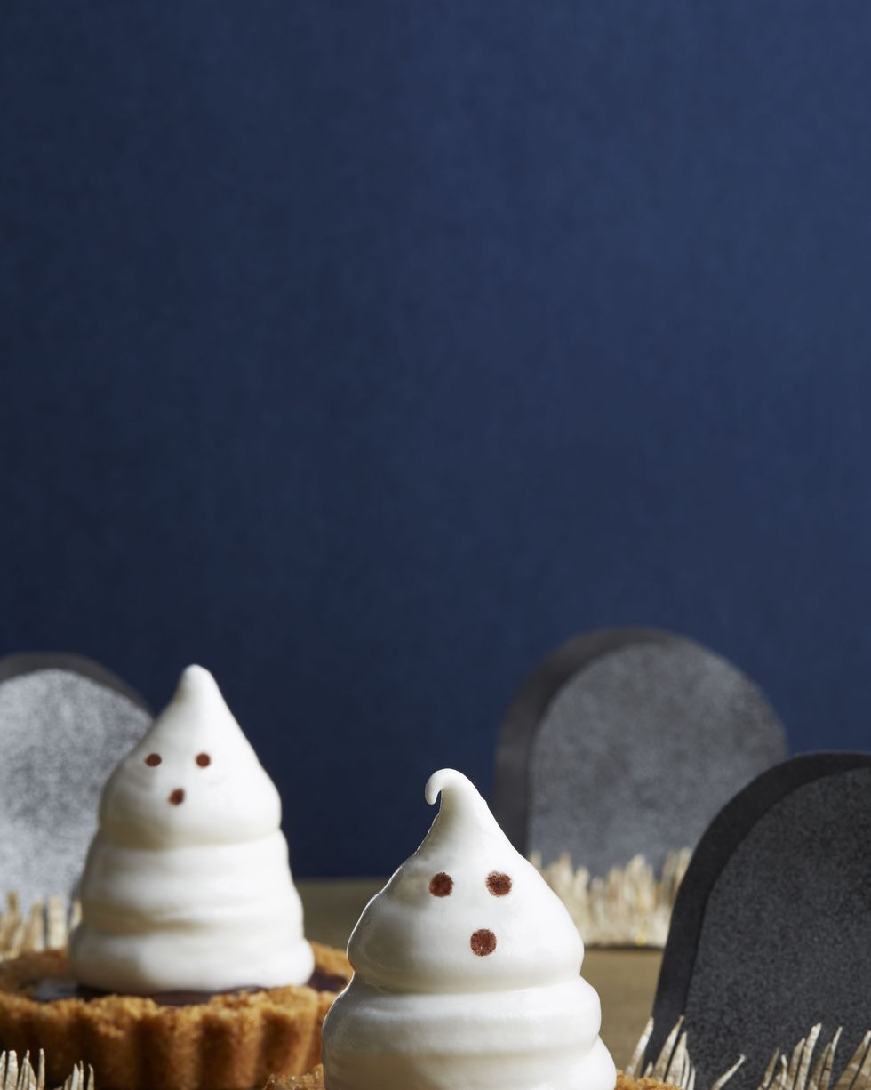 meringue ghost tartlets with paper tombstones arranged around them