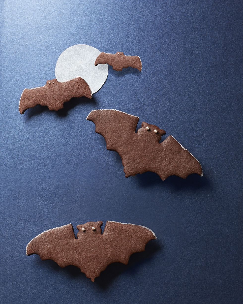 spiced chocolate bat cookies with sprinkle eyes on a black background