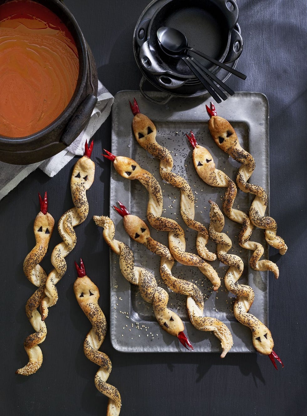 breadsticks twisted to look like snacks with eyes made of black olives and forked tongues made of dried chiles