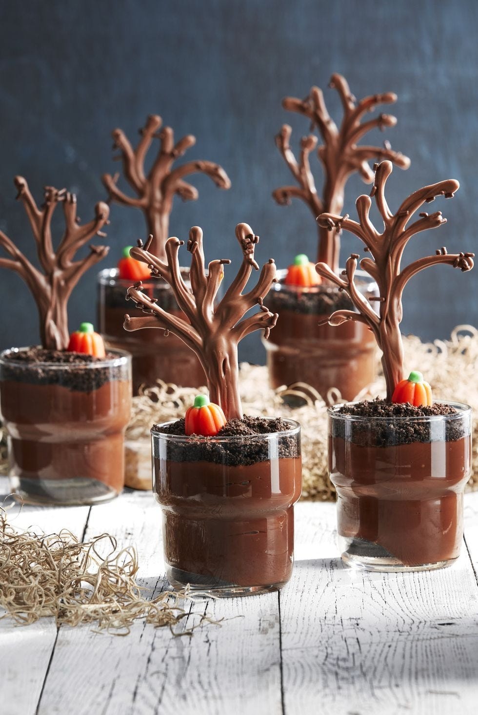 individual chocolate pudding cups with a chocolate tree and a candy pumpkin on top of each